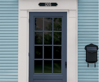 Blue front door with white trim and light-blue siding with black mailbox. House number is 1205.